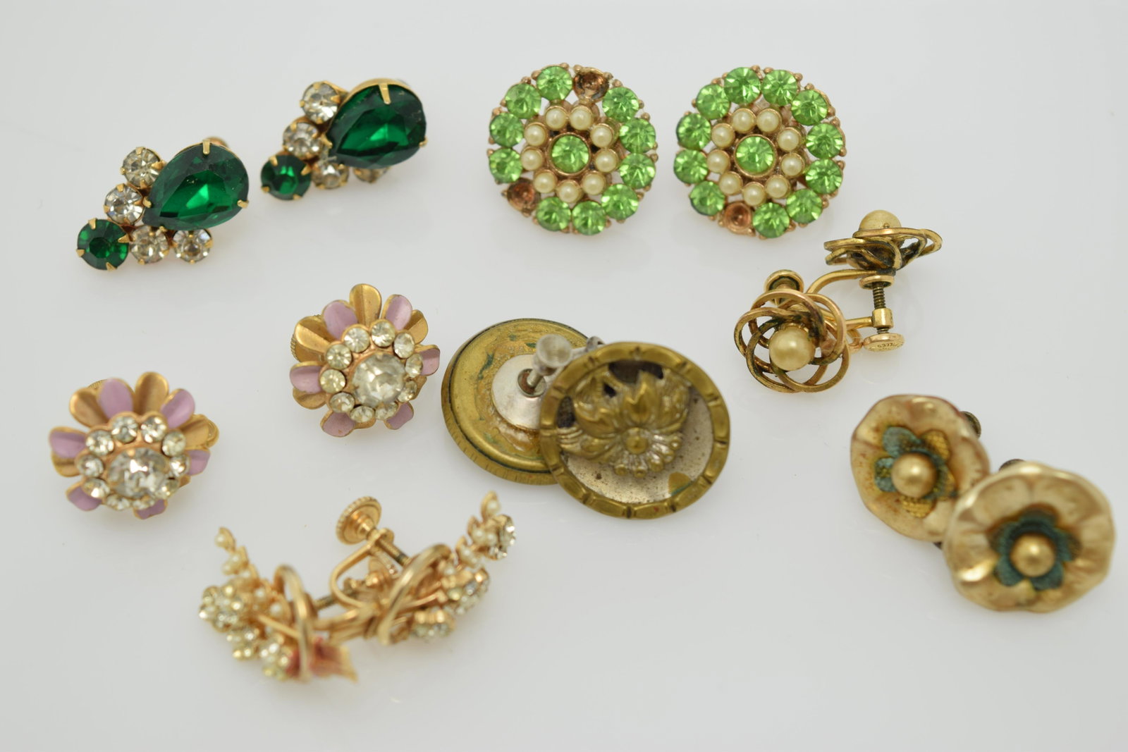 A lot of seven pairs of vintage screw back earrings.: A lot of 7 vintage screw back earrings consisting of a pair of dark green & clear rhinestones, a pair of light green & faux pearls. These are missing some of the green rhinestones. A pair of gold tone