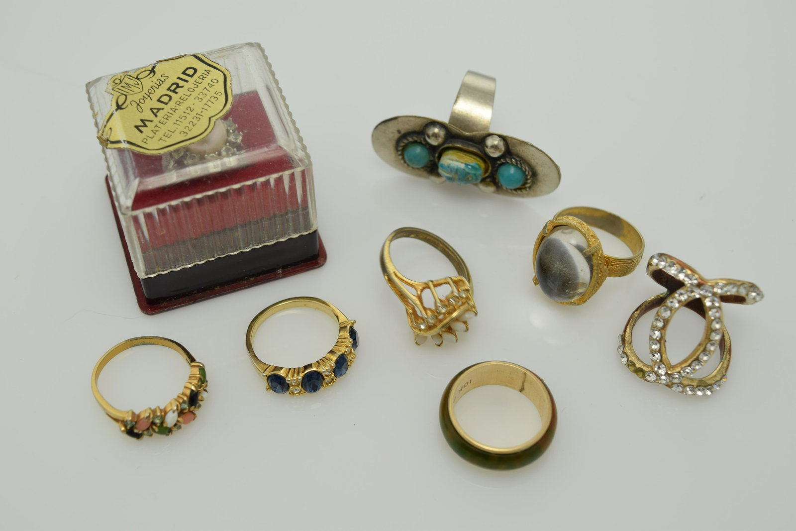 A lot of eight vintage rings.: A lot of 8 vintage rings. I is a wedding band style with green marbled wood & edged in 10k gold filled metal size 6 ring. 2 is an adjustable gold tone ring with a grey plastic oval stone. 3 is an adju