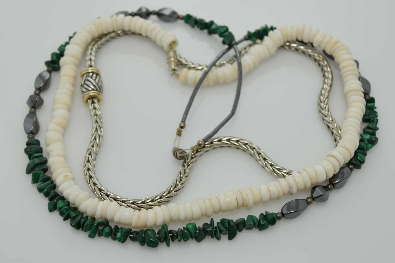 A lot of three vintage necklaces.: A lot of 3 vintage necklaces including an approx. 17" necklace of shells, an approx. 25" necklace of malachite nuggets & polished hematite stones, & an approx. 17-1/2" silver tone snake necklace w a m
