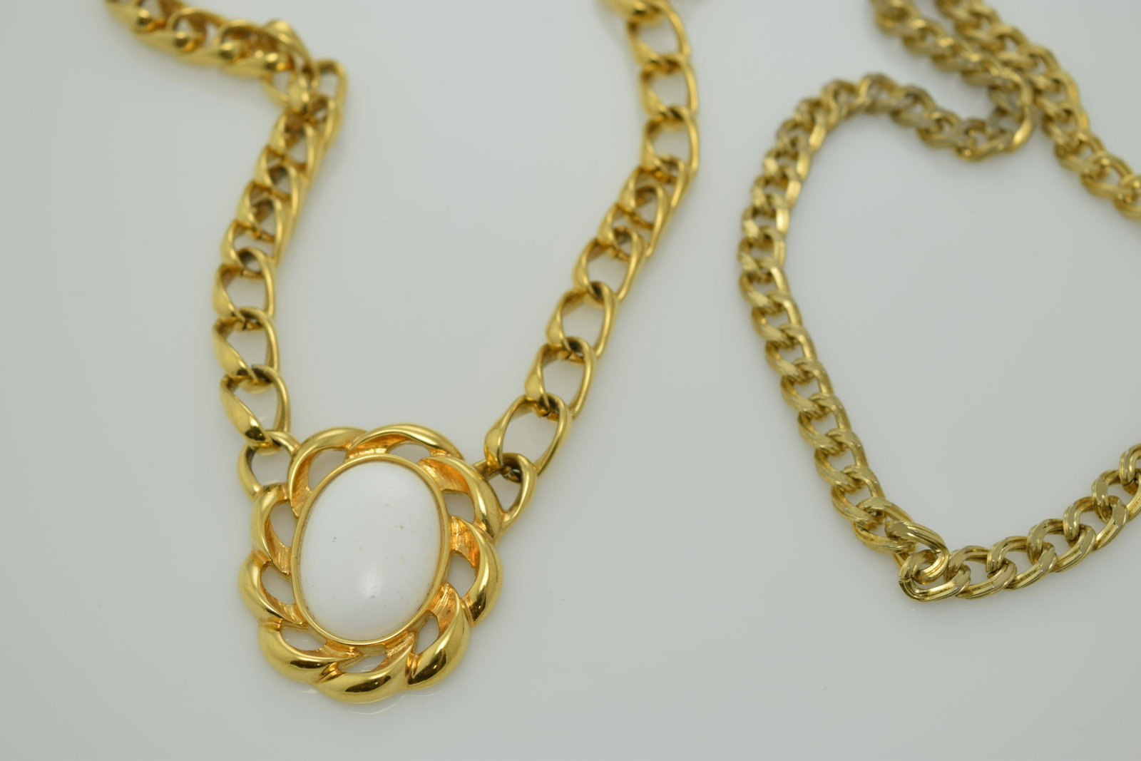 A lot of two vintage necklaces. One is marked Monet.: A lot of 2 vintage, gold tone necklaces. 1 is an approx. 18" chain necklace. The other is marked Monet & is approx. 19" w a white plastic center set in twisted gold tone metal. Both are in pre-owned c