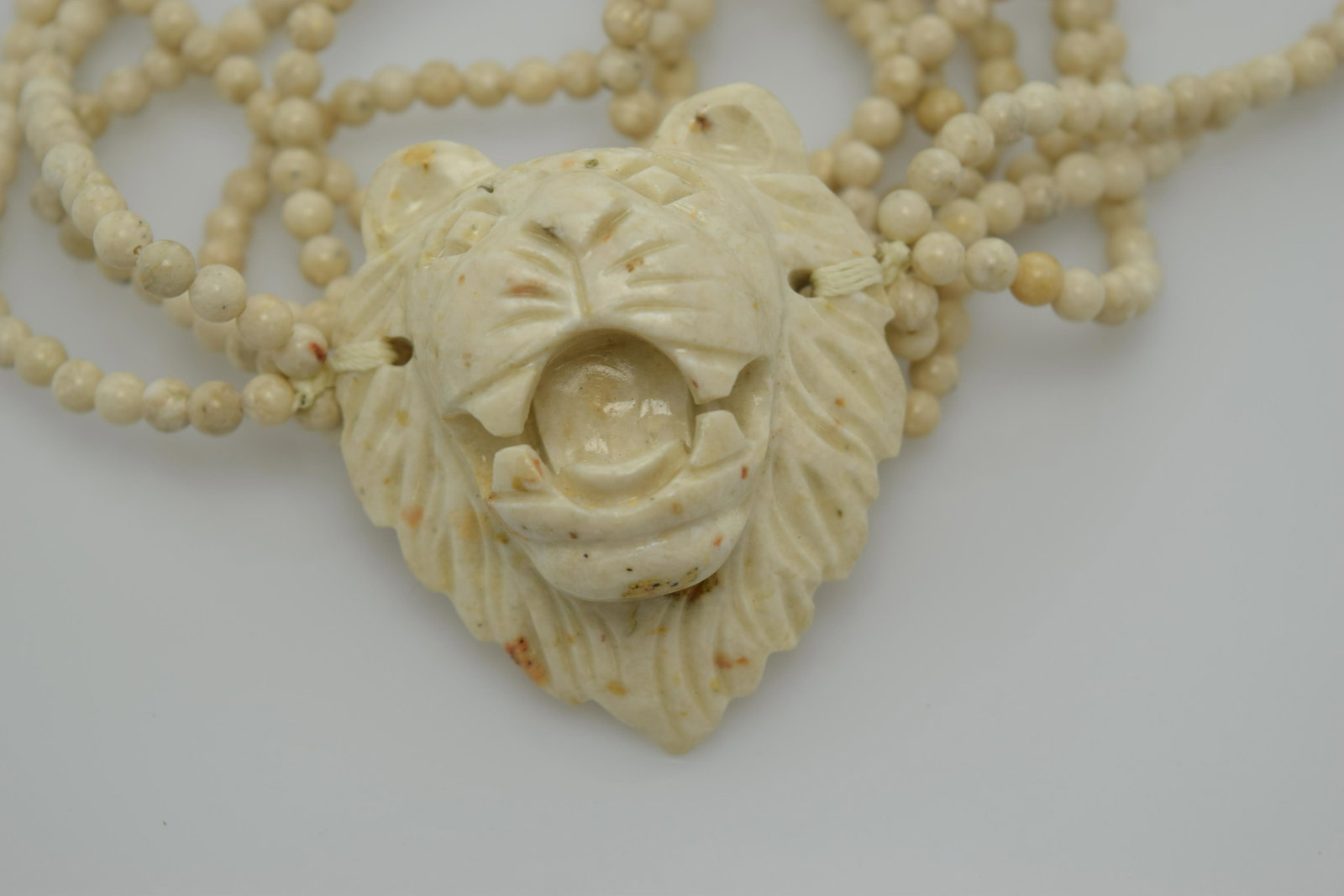 A vintage stone bead necklace with a carved lion face. (1 of 3)