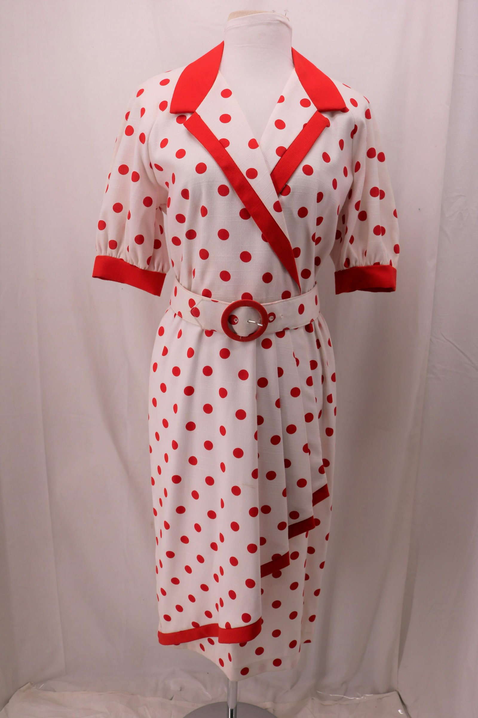 Vintage 1980's Sabino Red Polka Dot Dress: short puff sleeves with button cuff, convertible collar, shoulder pads, white poly blend with red polka dots, asymmetric pleated front hem, matching fabric buckle belt, Approx. 40" Bust, 32" Waist, so
