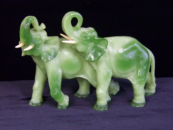 Carved Green Jade Elephants: Beautifully detailed, carved green jade elephants with their trunks raised in the air. Believe the tusks are ivory. Approximately 10" H x 16" L