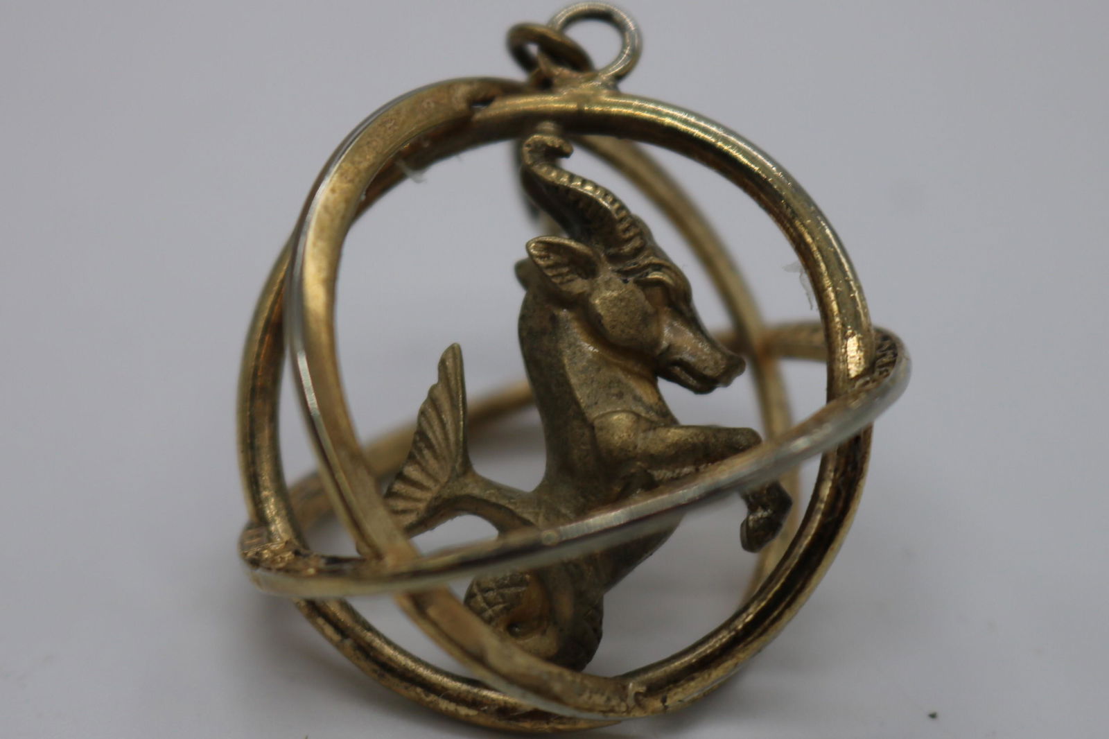 A signed Trifari, vintage, 1960's gold tone Capricorn: An approx. 1-1/2", vintage, 1960's , signed Trifari, gold tone, 3 D orb zodiac Capricorn pendant/charm. It is in pre-owned condition.
