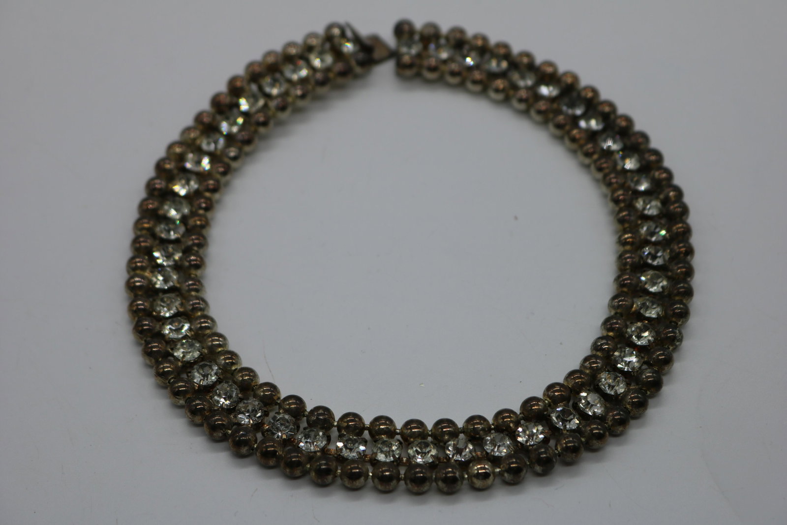 A vintage, silver tone, ball bead and rhinestone: An approx. 16", 3 row, silver tone ball bead necklace w round, prong set, clear rhinestones. In pre-owned condition.