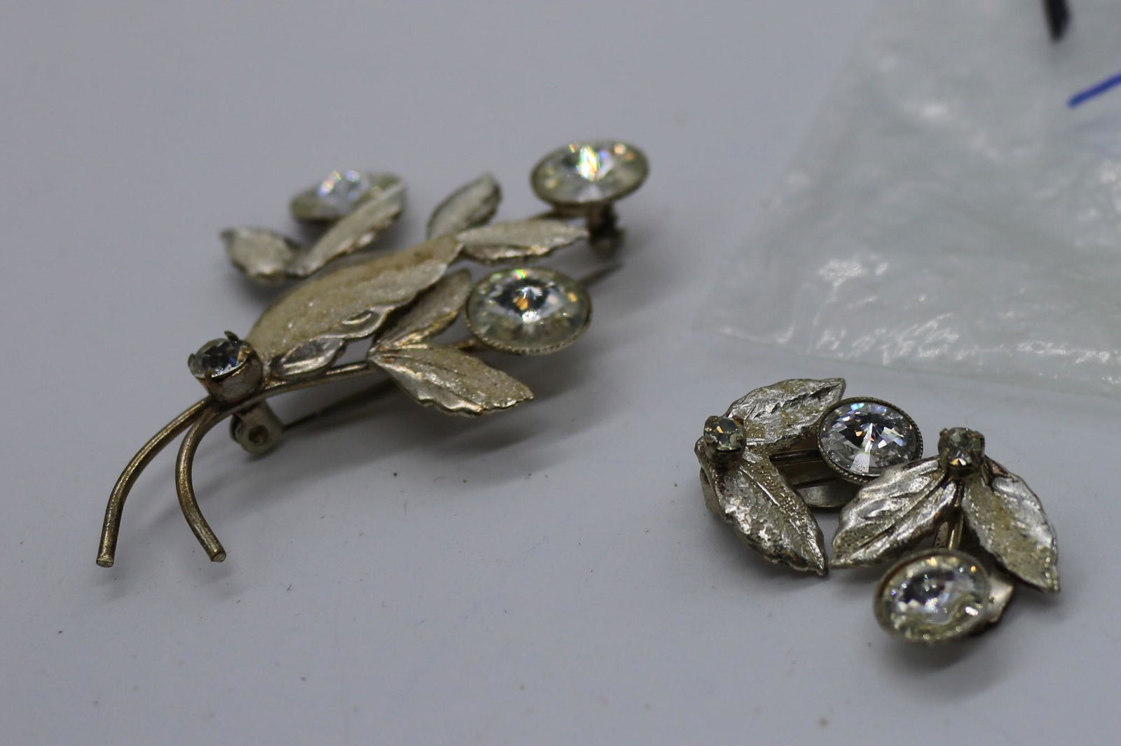 A vintage gold tone and clear Rivoli flower pin and: A vintage gold tone & clear Rivoli flower & leaf shape pin & clip on earring set. The pin is approx. 2-1/2" long. In pre-owned condition.