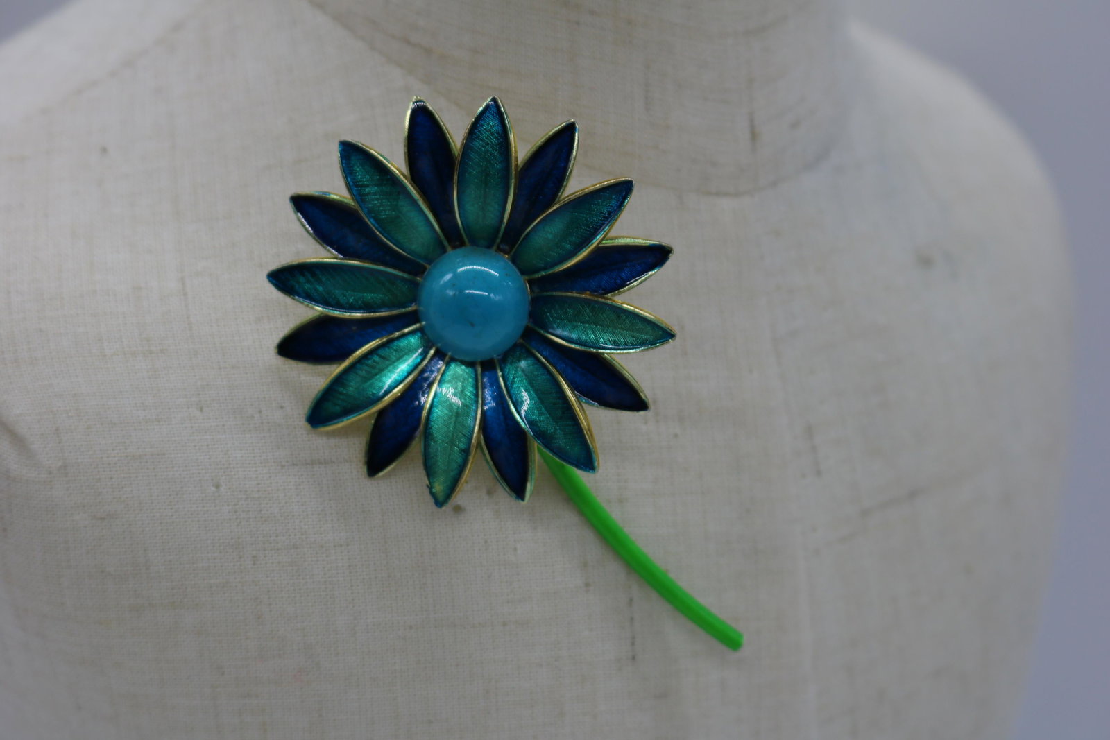 A German made blue and teal enamel flower pin/brooch.: An approx. 3-1/4" daisy pin w navy blue & teal enamel petals & a teal, plastic, cabochon center. It is signed made in Germany & is in good condition.