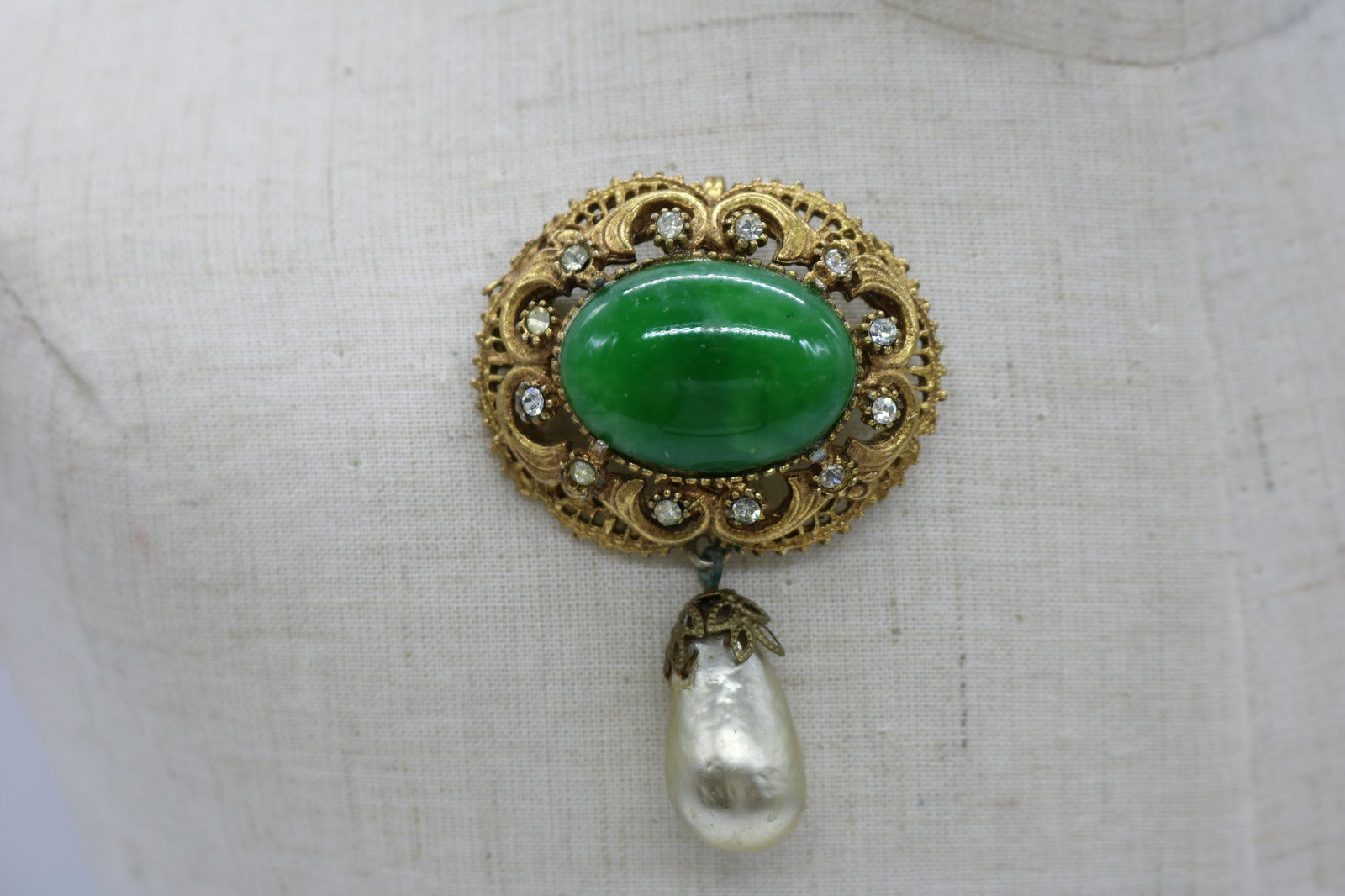 A vintage, gold tone pin with a green glass stone in (1 of 2)