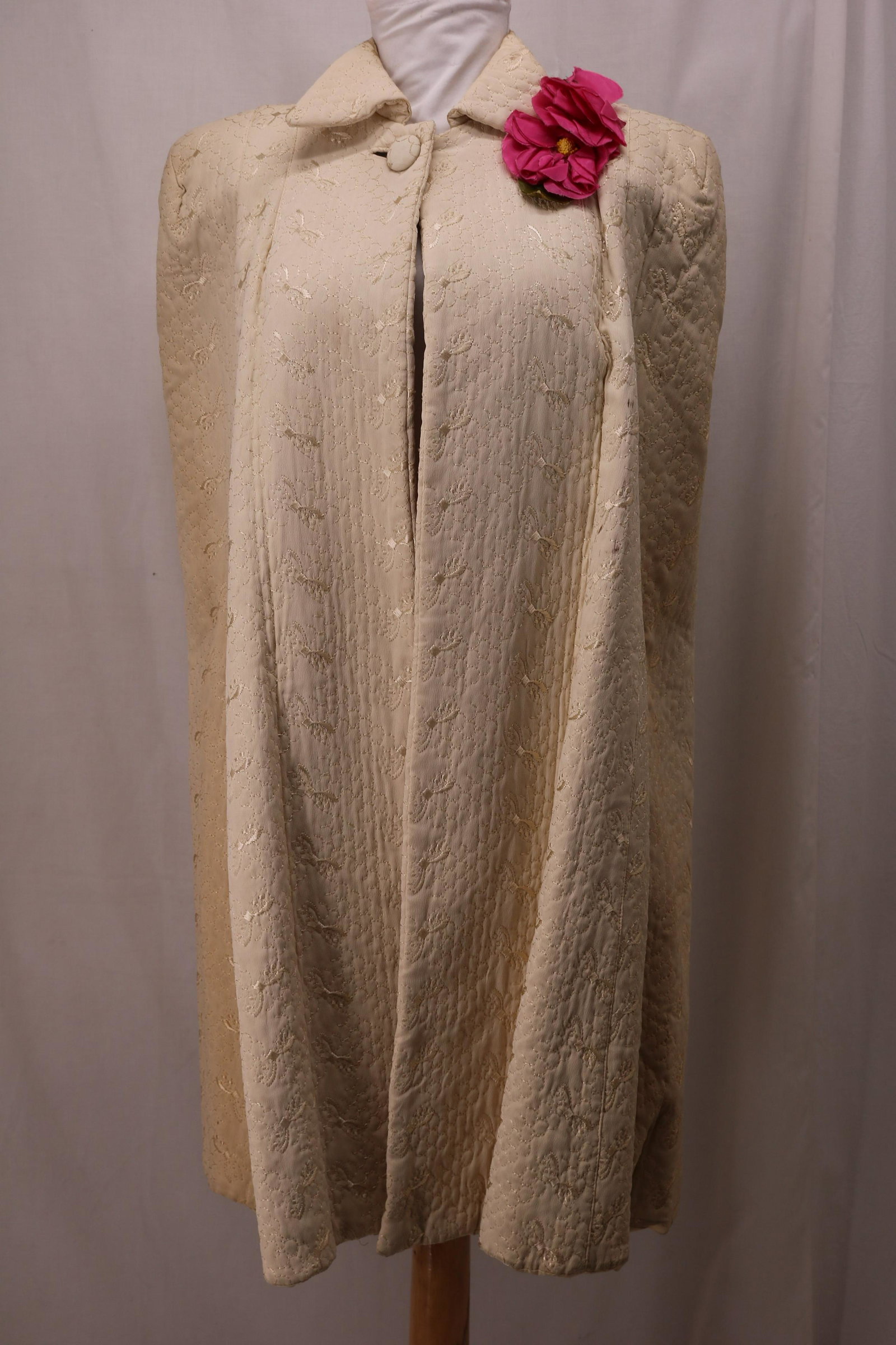 Vintage 1940's Ladies Quilted Cape: Ivory quilted cape, silk embroidery, silk blend lining, winged collar, button closure at collar, flower detail left of collar, some scuff marks on front, see photos.