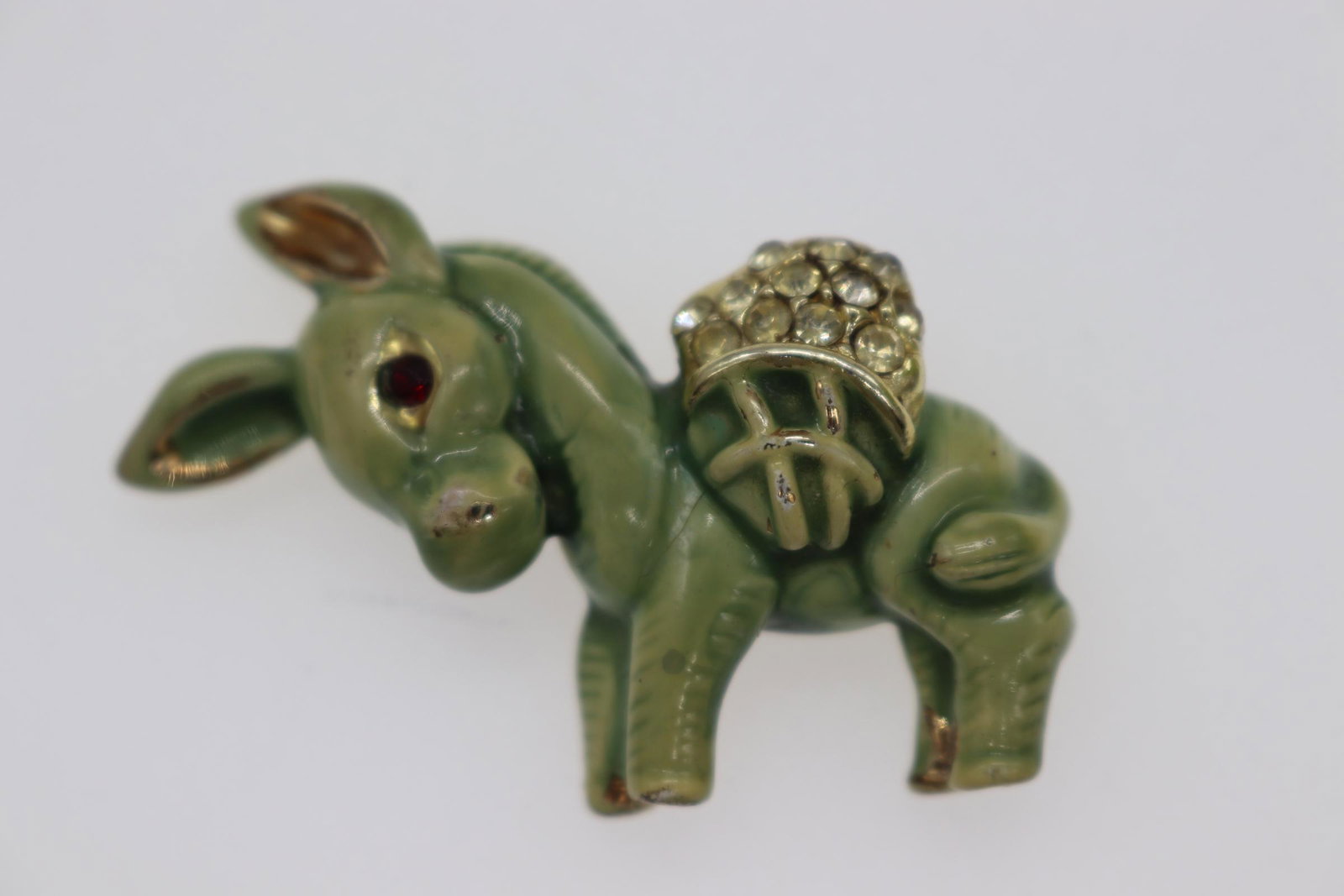 Vintage Green Enamel & Rhinestone Donkey Brooch: green enamel donkey with gold-tone painted ears & hooves, rhinestone pack, & garnet-colored stone eyes, Approx. 2", see photos.
