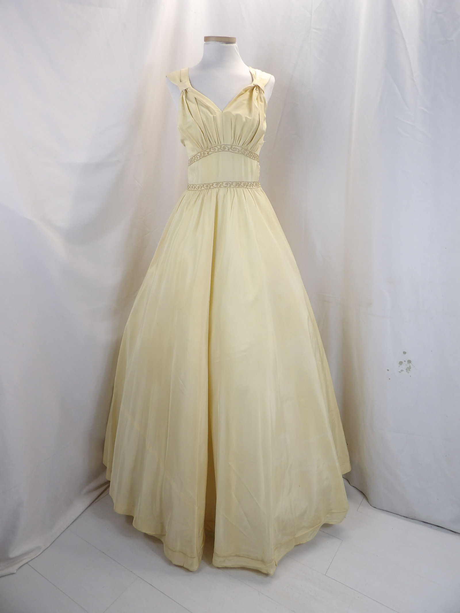VINTAGE 1930'S OFF WHITE TAFFETA GOWN WITH CORDE TRIM: APPROX. 32 BUST, 25 WAIST. HAS A COUPLE OF SMALL STAINS & HAS SOME SMALL HOLES. NEEDS SEAM REPAIR AT THE BOTTOM OF THE V NECK. SEE PHOTOS.
