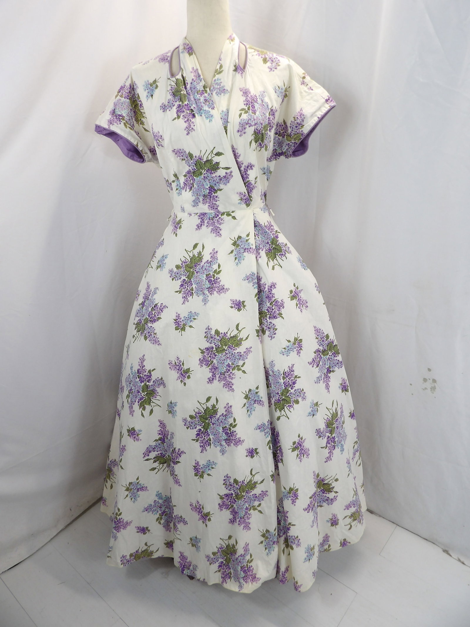 VINTAGE 1950'S EVELYN PEARSON PURPLE COTTON LILAC PRINT LOUNGING ROBE: APPROX. 36 BUST, 26 WAIST. HAS HOLE UNDER ARM & ANOTHER SMALL HOLE WITH SMALL SPOTS. SEE PHOTOS.