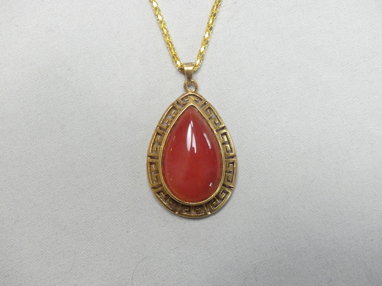 Vintage Gold Tone Carnelian Pendant: Pear shaped carnelian pendant w/ greek key motif approx. 1" x 1.25"