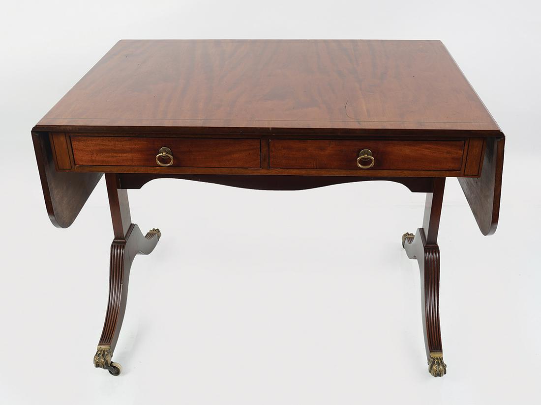 EDWARDIAN MAHOGANY SOFA TABLE: Stamped Warring & Gillows, the rectangular top with drop leaves above real and opposing faux drawers, raised on panelled and sabre ends, terminating on brass claw feet and castors 72 cm. high; 96 cm.
