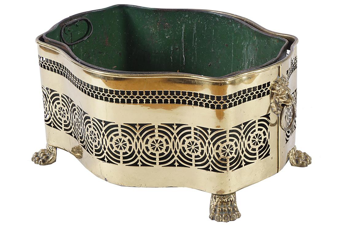 LARGE EDWARDIAN BRASS LOG BOX: of oval serpentine form, furnished with a metal liner, the pierced body, furnished with lion mask handles 27 cm. high; 54 cm. wide; 41 cm. deep
