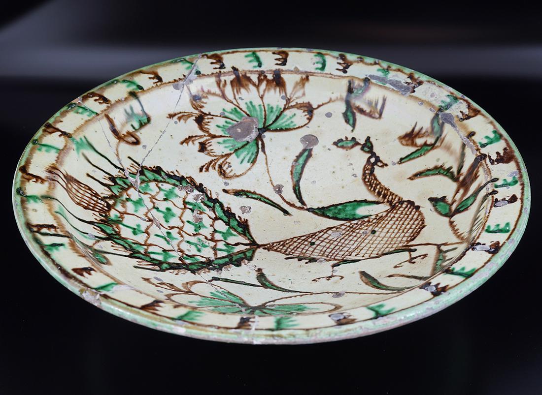 EARLY ISLAMIC CHARGER: yellow ochre ground with painted bird and floral decoration 9 cm. high; 33 cm. diameter