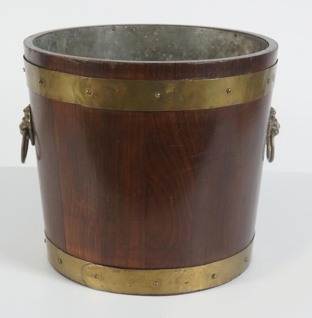 19TH-CENTURY BRASS BOUND LOG BOX: of circular tapered form, furnished with lion mask handles 34 cm. high; 37 cm. diameter