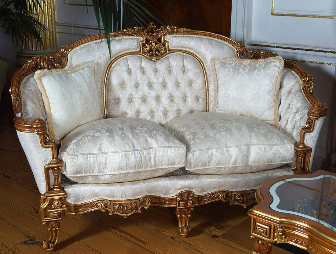 PAIR OF CARVED AND PARCEL GILT SETTEES: each with a serpentine crest rail centred by a torch and quiver motif above a damask upholstered panelled back and loose cushioned seat raised on cabriole legs to the fore Provenance: Castlehyde House