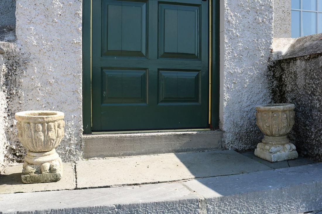 PAIR OF ITALIANATE STONE APOSTLE URNS: each of bowl form raised on a turned stem and recumbent lion mounted square base 40 cm. high; 29 cm. diameter