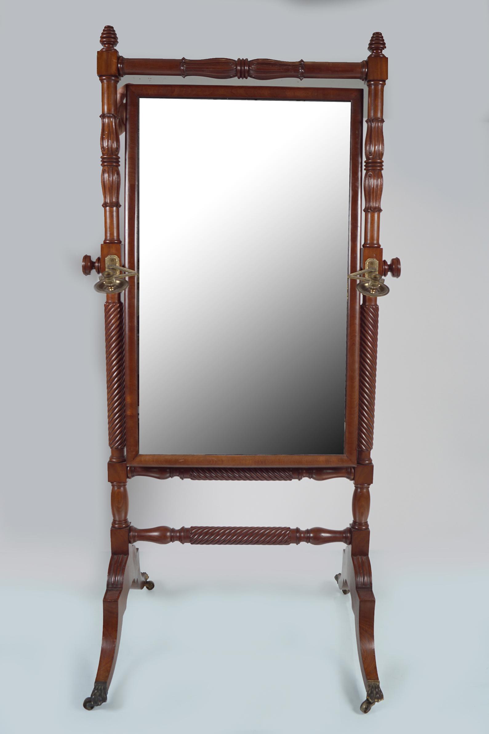 REGENCY PERIOD MAHOGANY DRESSING MIRROR: the rectangular plate within a round over frame, suspended on spiral turned pillars and sabre ends, joined by a turned stretcher rail, terminating on brass claw feet and castors. 183 cm. high; 79 cm.
