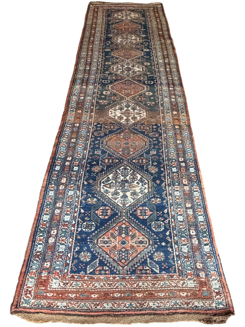 EARLY 20TH-CENTURY NW PERSIAN BAKHSHAYESH RUNNER: CIRCA 1910, Of elongated form, the deep indigo ground populated by a continuous row of large, angular lozenge medallions in madder red and ivory, each enclosing stylised geometric and tribal motif. Th