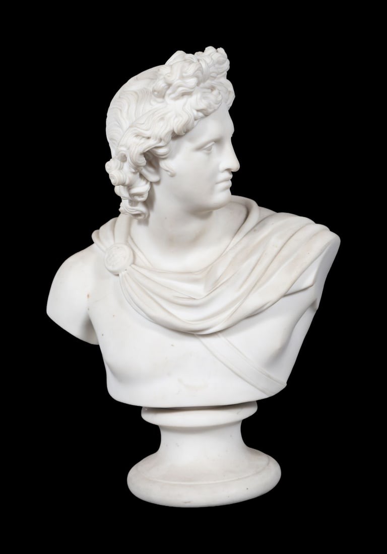 19TH-CENTURY PARIAN BUST OF APOLLO: A 19th-century Parian porcelain bust of Apollo, modelled in classical style with flowing hair and draped cloak, raised on a circular socle. PORCELAIN