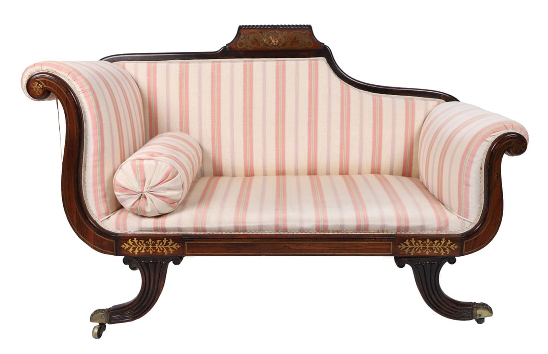 REGENCY ROSEWOOD CHAISE LONGUE: EARLY 19TH CENTURY, A Regency period mahogany framed chaise longue, the shaped and scrolled ends with ebonised line inlay and decorative panels, raised on reeded sabre supports terminating in brass ca