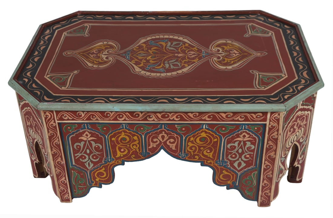 20TH - CENTURY MOROCCAN PAINTED COFFEE TABLE: A 20th-century Moroccan coffee table of rectangular form, richly painted in red, blue, and ochre with stylised arabesques and geometric ornament, the frieze with pierced Moorish arches. FURNITURE