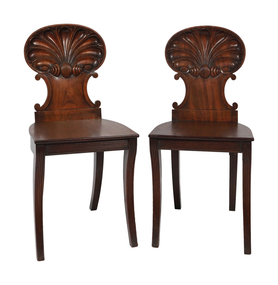 PAIR MAHOGANY SCALLOP-BACK HALL CHAIRS: REGENCY PERIOD, Each with shaped cresting and solid seat, the backs carved with scallop and moulded detail, raised on square tapering legs. FURNITURE