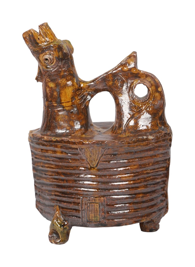A ZOOMORPHIC CERAMIC GLAZED DRINKING VESSEL: The stem in the form of a mythological creature, and the body of oval form, supported by three paw feet CERAMICS