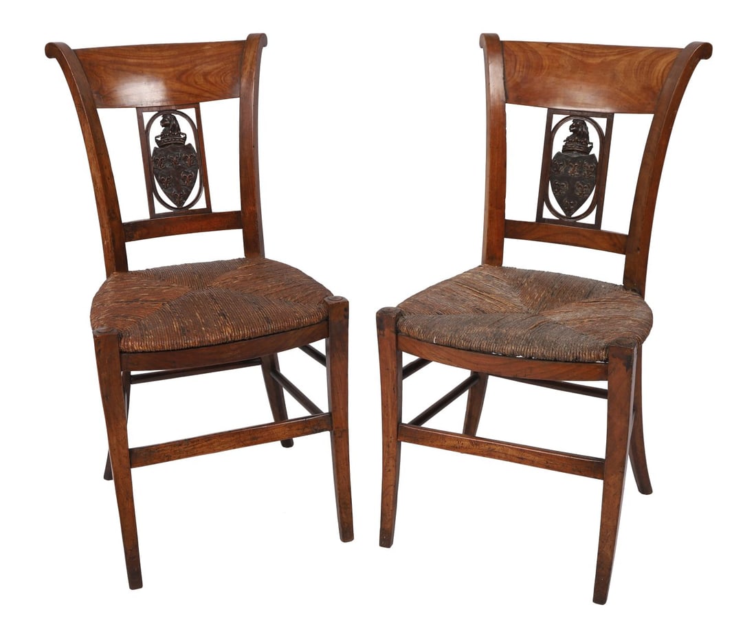 PAIR OF FRENCH PROVINCIAL WALNUT CHAIRS: LATE 18TH / EARLY 19TH - CENTURY. A pair of French provincial walnut chairs, each with shaped top rail above a pierced splat centred with an oval reserve carved in relief with a heraldic-style device,