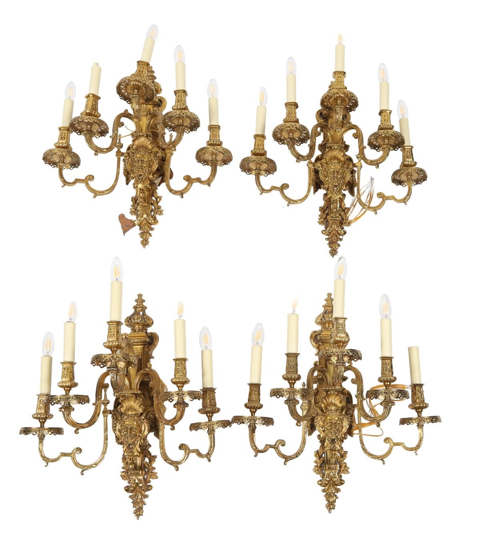 SET OF FOUR ORMOLU FOUR-BRANCH WALL SCONCES: Each with scrolling arms issuing from a foliate backplate, cast with acanthus and floral ornament, fitted for electricity. LIGHTING