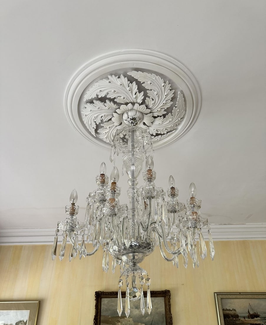 NINE-BRANCH WATERFORD CRYSTAL CHANDELIER: the central baluster issuing scrolling arms with faceted drops and prism lustres, fitted for electricity. LIGHTING