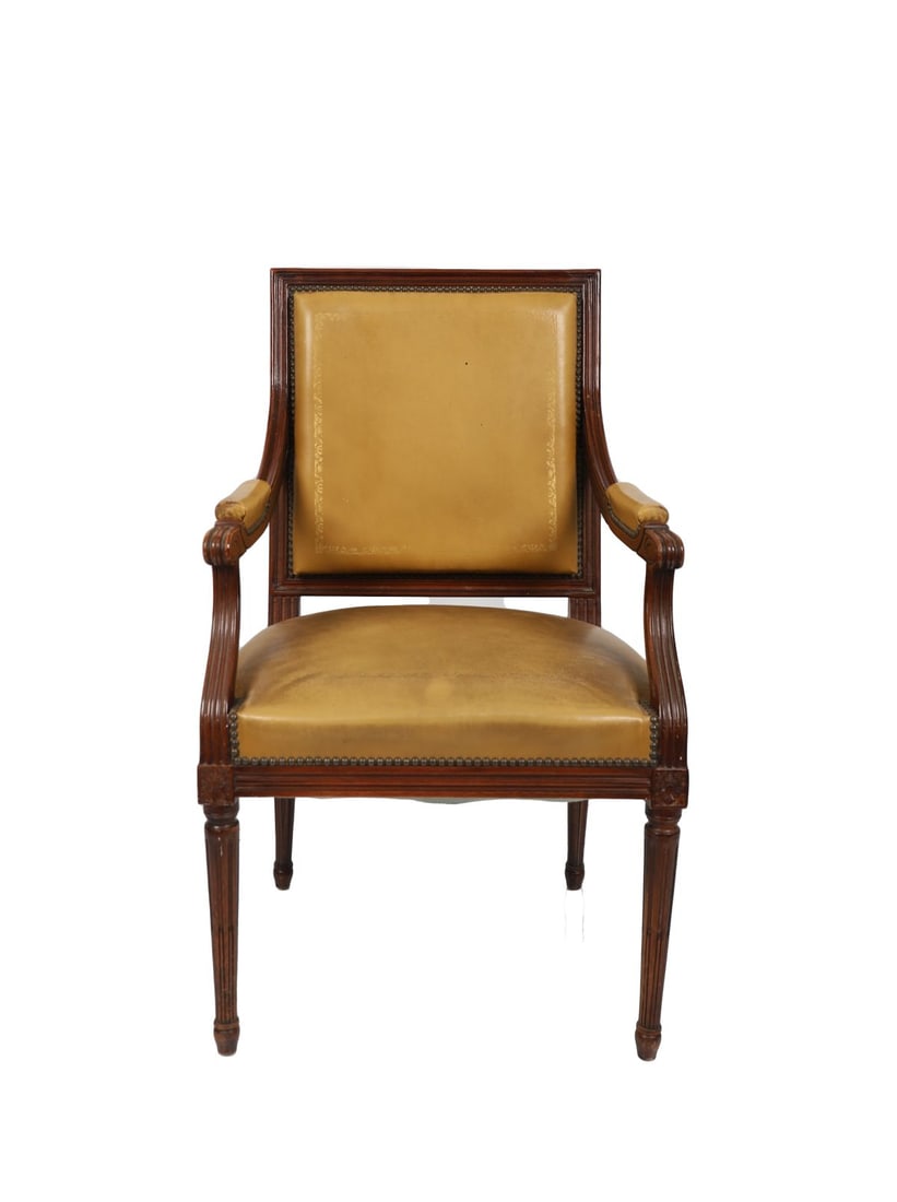 FRENCH LOUIS XVI-STYLE MAHOGANY FAUTEUIL: HIDE UPHOLSTERED, Late 19th century. The square tooled padded back, arms, and seat upholstered in olive-green leather with brass nail-head trim, the moulded frame with fluted supports and tapered legs