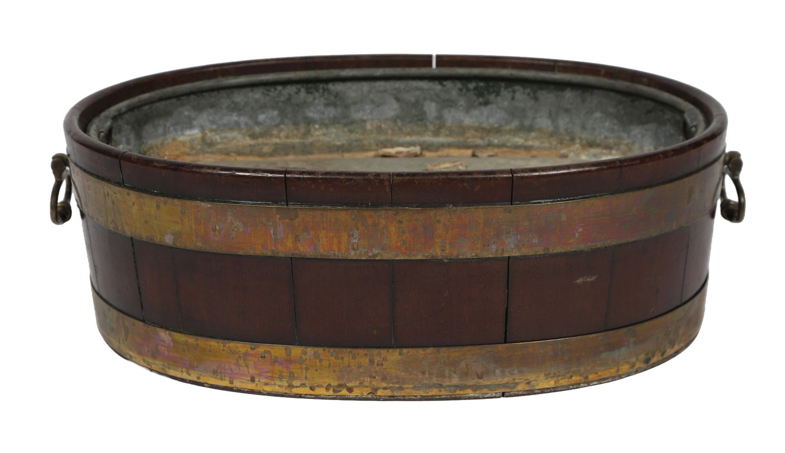 GEORGE III MAHOGANY & BRASS-BOUND WINE CELLARETTE: Of oval coopered form, the body with brass bands and carrying handles, retaining a lined interior, raised on a spreading foot. FURNITURE