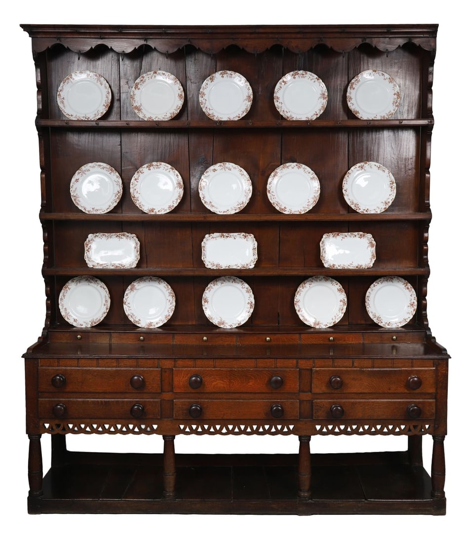 18TH - CENTURY WELSH OAK DRESSER: Large oak dresser with open plate rack above, fitted with three graduated shelves beneath a shaped cornice with hanging hooks, over a base with an arrangement of drawers and cupboard space, raised on 