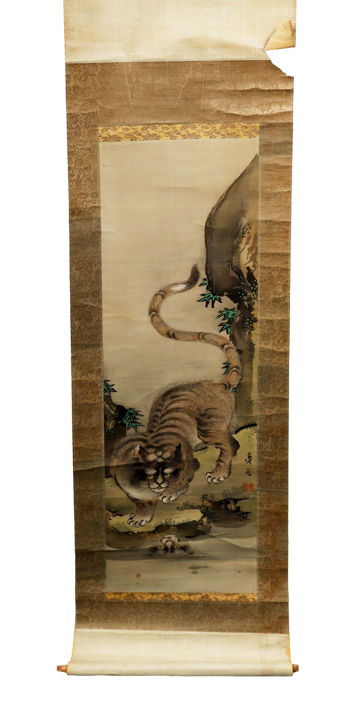 JAPANESE HANGING SCROLL WITH TIGER: Painted on silk, depicting a prowling tiger beside a rocky outcrop, with calligraphic inscription and seal, mounted on a brocade ground. JAPANESE
