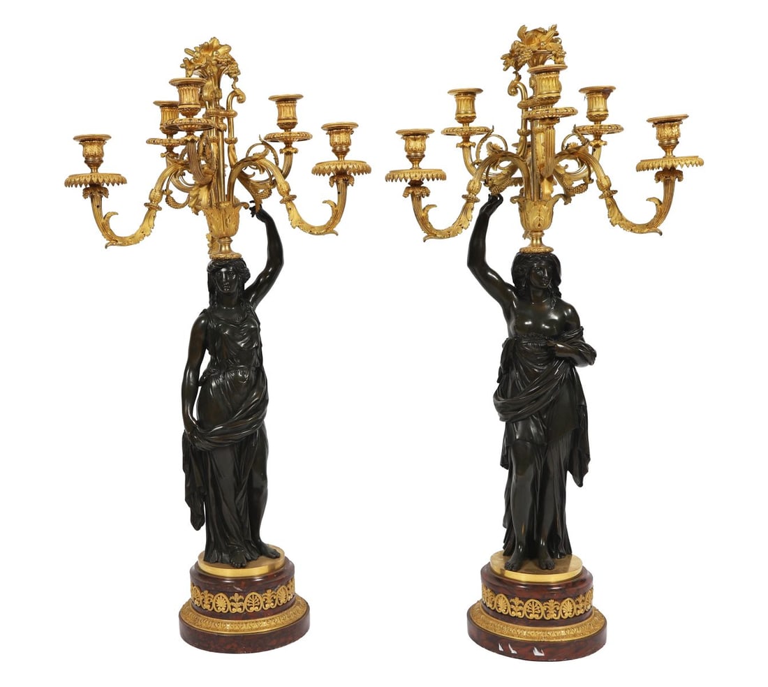 PR 19TH-CENTURY REGENCY BRONZE FIGURAL CANDELABRA: BRONZE AND ORMOLU, Each cast as a classical female figure supporting a multi-branch ormolu candelabrum, raised on circular bases, the contrast between dark patinated bronze and gilt mounts typical of 