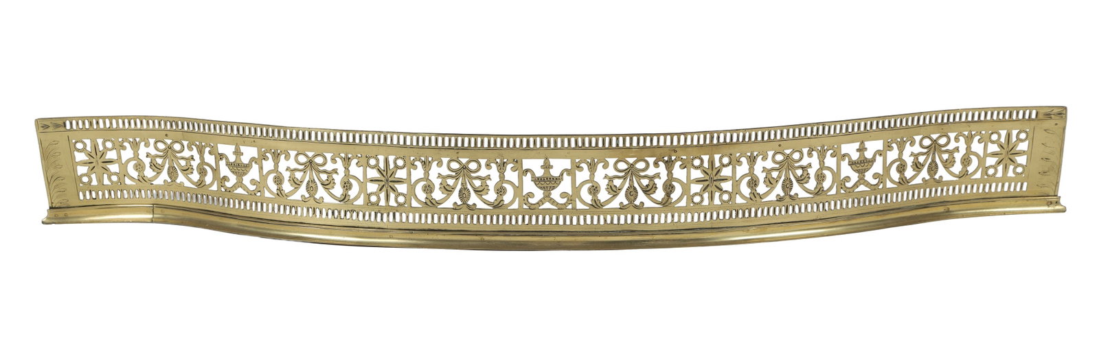GEORGE III PERIOD PIERCED BRASS FIRE FENDER: a Dublin George III period brass fire fender of serpentine outline, the pierced gallery cast with classical motifs and paterae, raised on supports with circular medallions and finials. FIRE FURNITURE