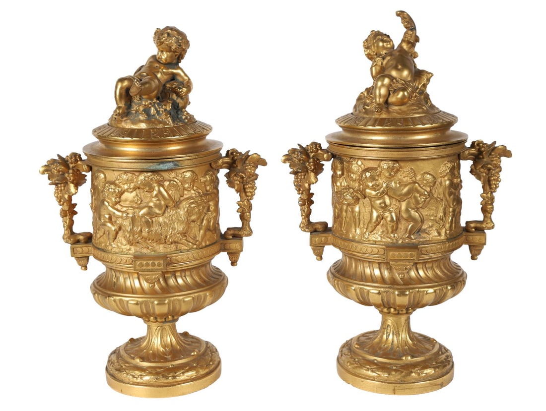 PAIR OF 19TH-CENTURY ORMOLU URNS: each with a frieze of bacchantes cherubs, with vine scroll handles, raised on a circular foot. SCULPTURE