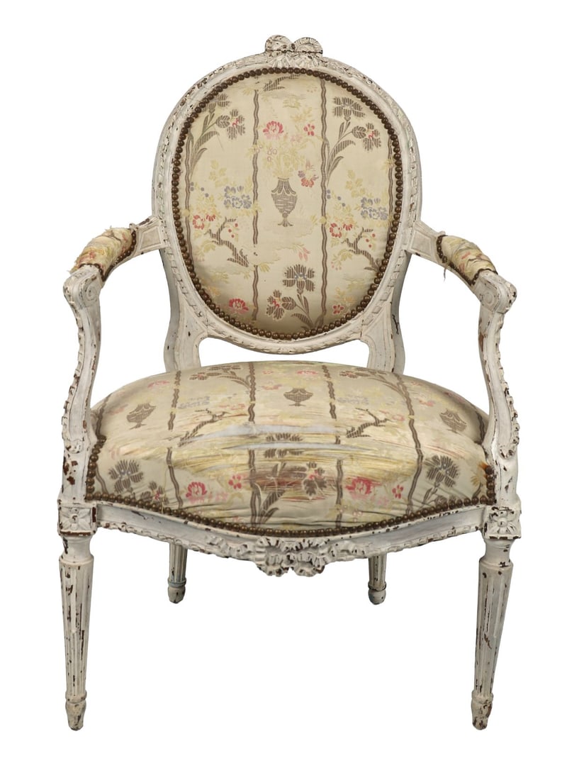 18TH - CENTURY LOUIS XVI PAINTED FAUTEUIL: A French Louis XVI period carved fauteuil with oval padded back, scrolling arms, and serpentine seat, painted frame with floral carved crest, upholstered in floral damask. FURNITURE