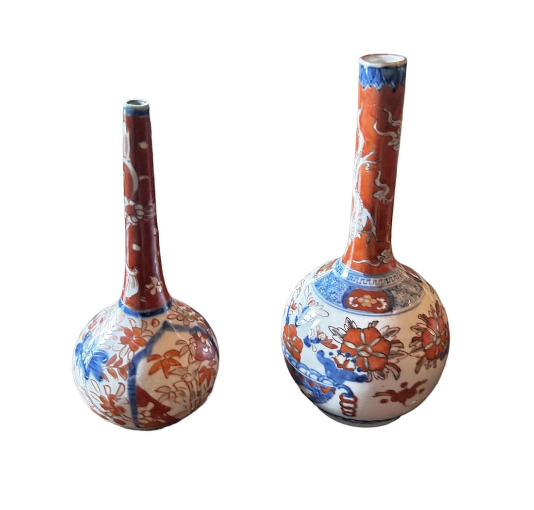 TWO JAPANESE IMARI BOTTLE SHAPED VASES: Two Japanese Imari bottle-shaped vases, each with elongated neck and globular body, decorated with floral motifs in iron-red and blue. JAPANESE