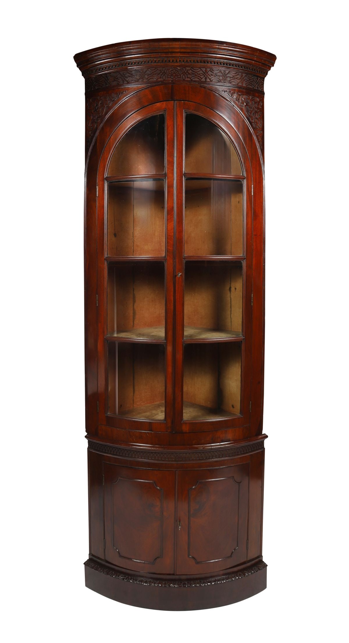 GEORGIAN MAHOGANY BOWFRONT CORNER CABINET: The upper section with a pierced and shaped gallery above astragal-glazed doors enclosing shelves, the lower section with a bowfront cupboard, the whole with carved detail and of tall, elegant proport