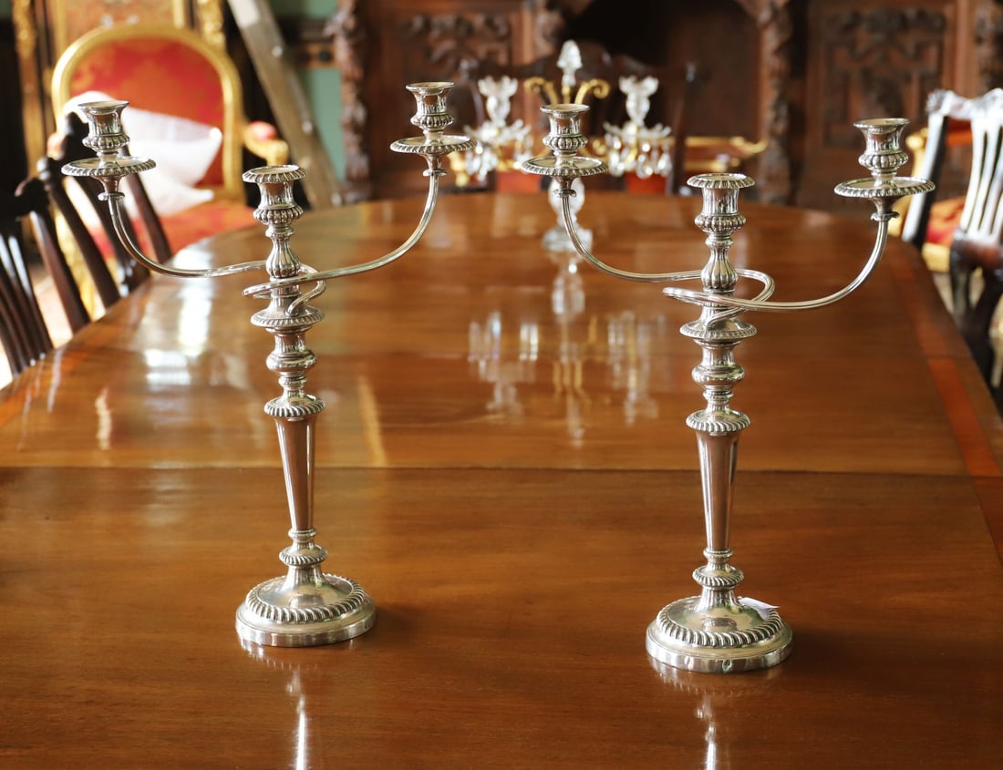 PAIR OF LARGE SHEFFIELD PLATE CANDELABRA: A pair of large Sheffield plate candelabra, each with a central baluster stem issuing multiple scrolling branches with detachable nozzles and drip pans, raised on circular bases with reeded and