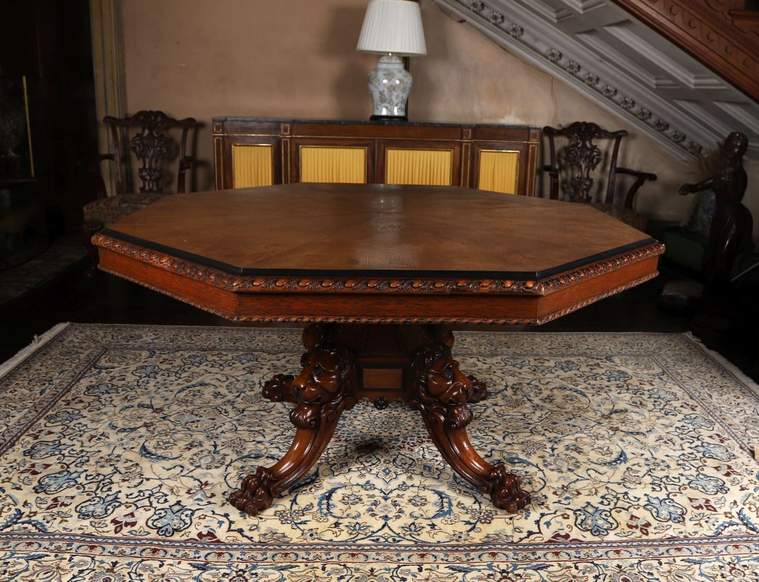 IRISH WILLIAM IV POLLARD OAK CENTRE TABLE: The octagonal top with moulded edge above a frieze carved with repeating detail, raised on a central column supported by four boldly carved legs with lion mask terminals and claw feet, the timber with