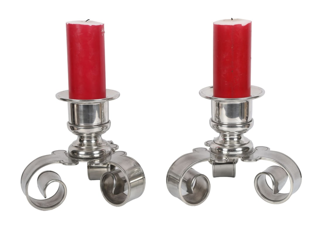 PR LATE 20TH-CENTURY SILVERED METAL CANDLESTICKS: Each of modern design with circular nozzle and broad drip pan, raised on stylised scroll-form bases. LIGHTING