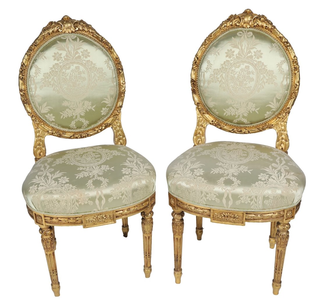 PAIR OF 19TH-CENTURY CARVED GILTWOOD SIDE CHAIRS: Each with oval back and foliate-carved frame, upholstered seat and back panel, raised on fluted tapering legs. FURNITURE