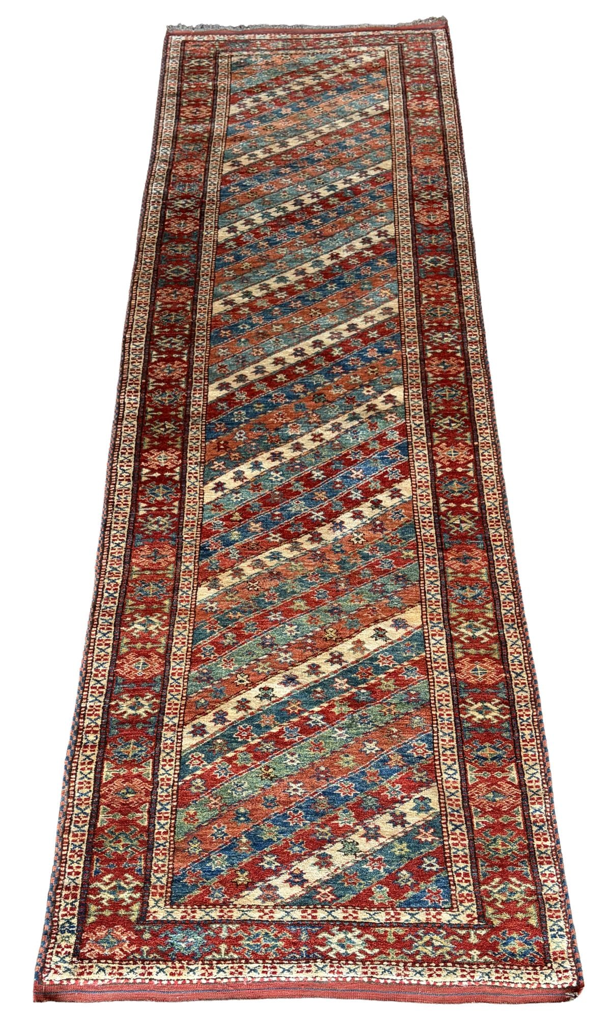 20TH - CENTURY CAUCASIAN GENDJE RUNNER: The field composed of distinctive diagonal bands in polychrome tones, filled with small-scale geometric motifs, enclosed within a red border of repeating hooked lozenge devices and multiple guard stri