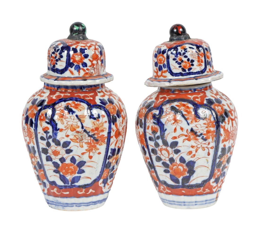 A PAIR OF JAPANESE IMARI LIDDED URNS: A pair of Japanese Imari lidded urns, of baluster form, decorated with scrolling foliage and floral panels, with domed covers. JAPANESE