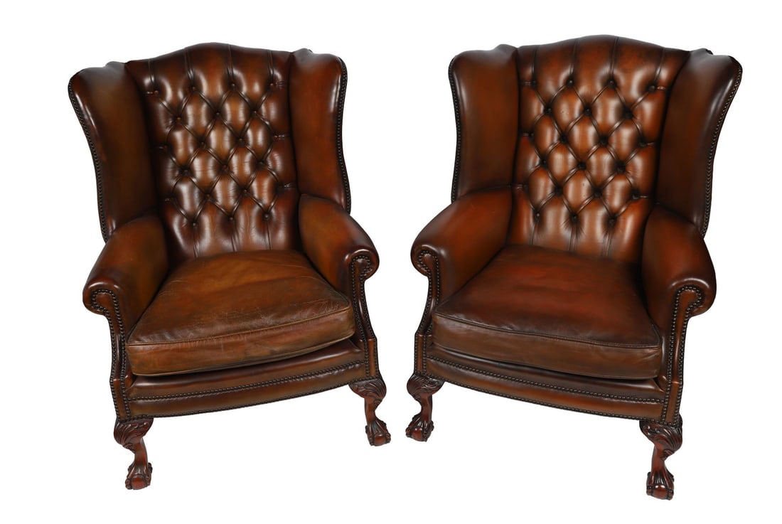 PAIR OF LEATHER WINGBACK ARMCHAIRS: Each with deep buttoned back and scroll arms upholstered in brown leather, raised on mahogany legs terminating in claw and ball feet. FURNITURE